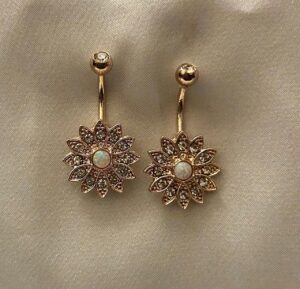 Golden daisy-shaped earrings with opal center and intricate crystal-studded petals, hanging elegantly from a gold stud